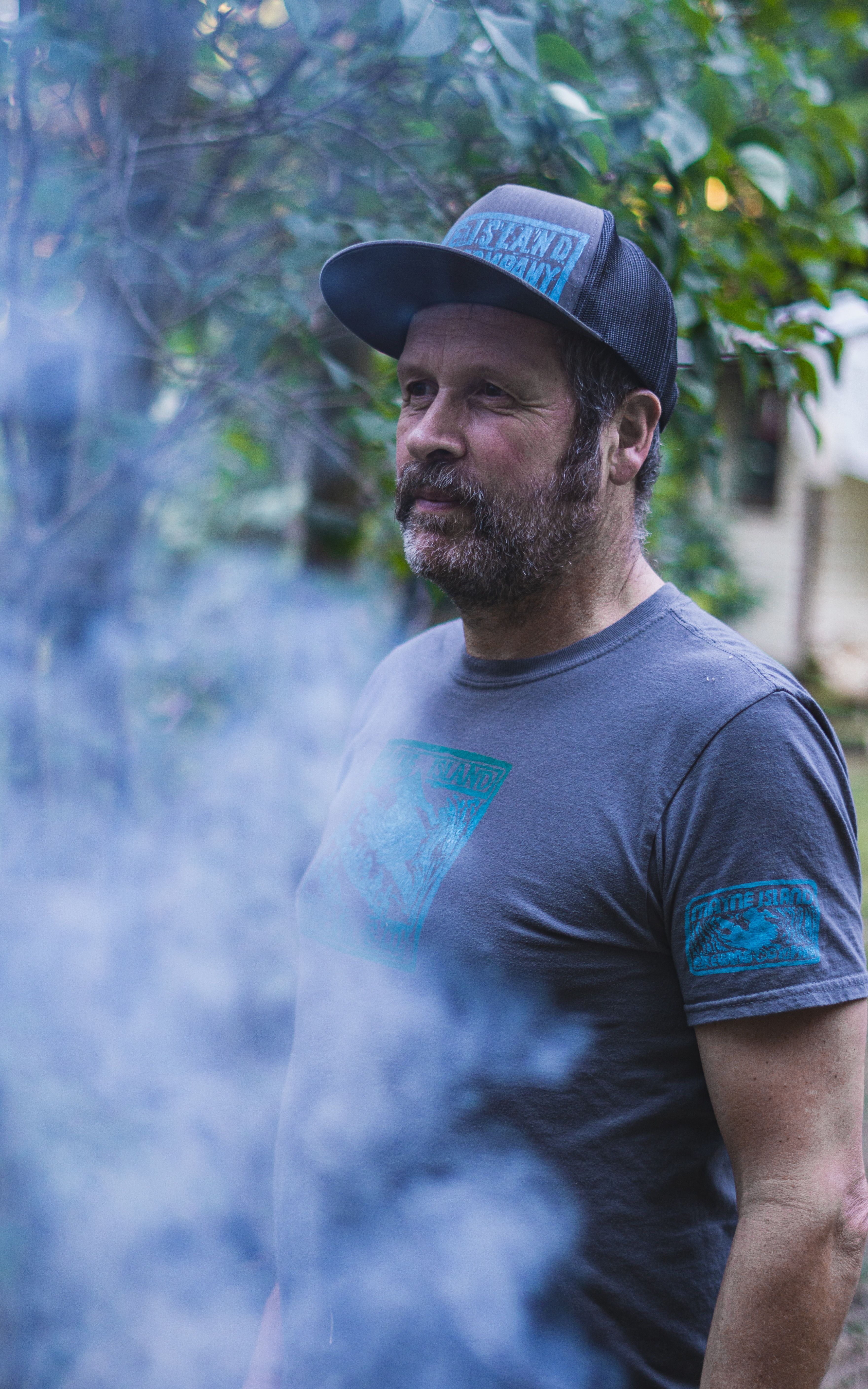 Man in a cap standing outdoors in wood smoke