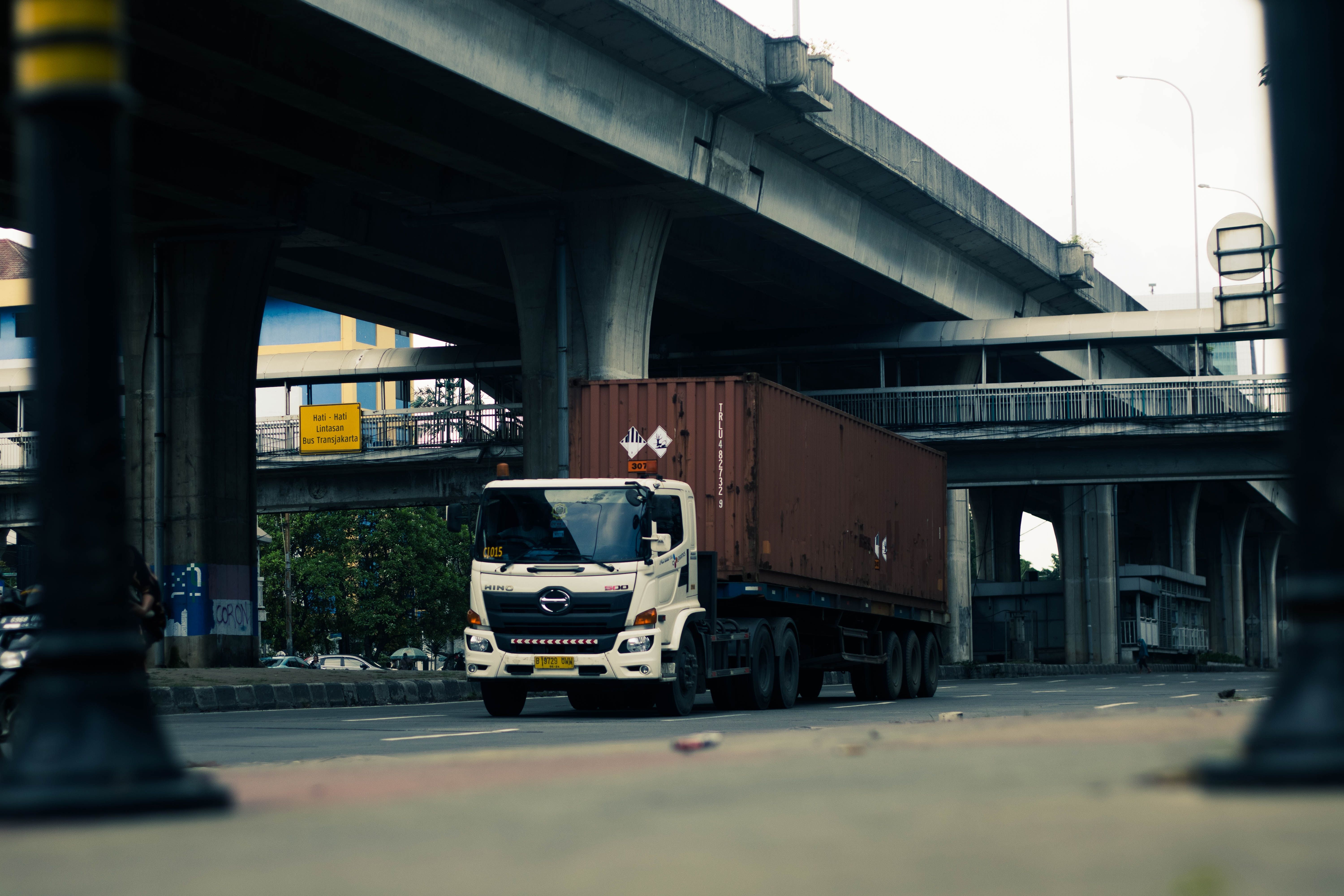 Container truck driving under a highway overpass