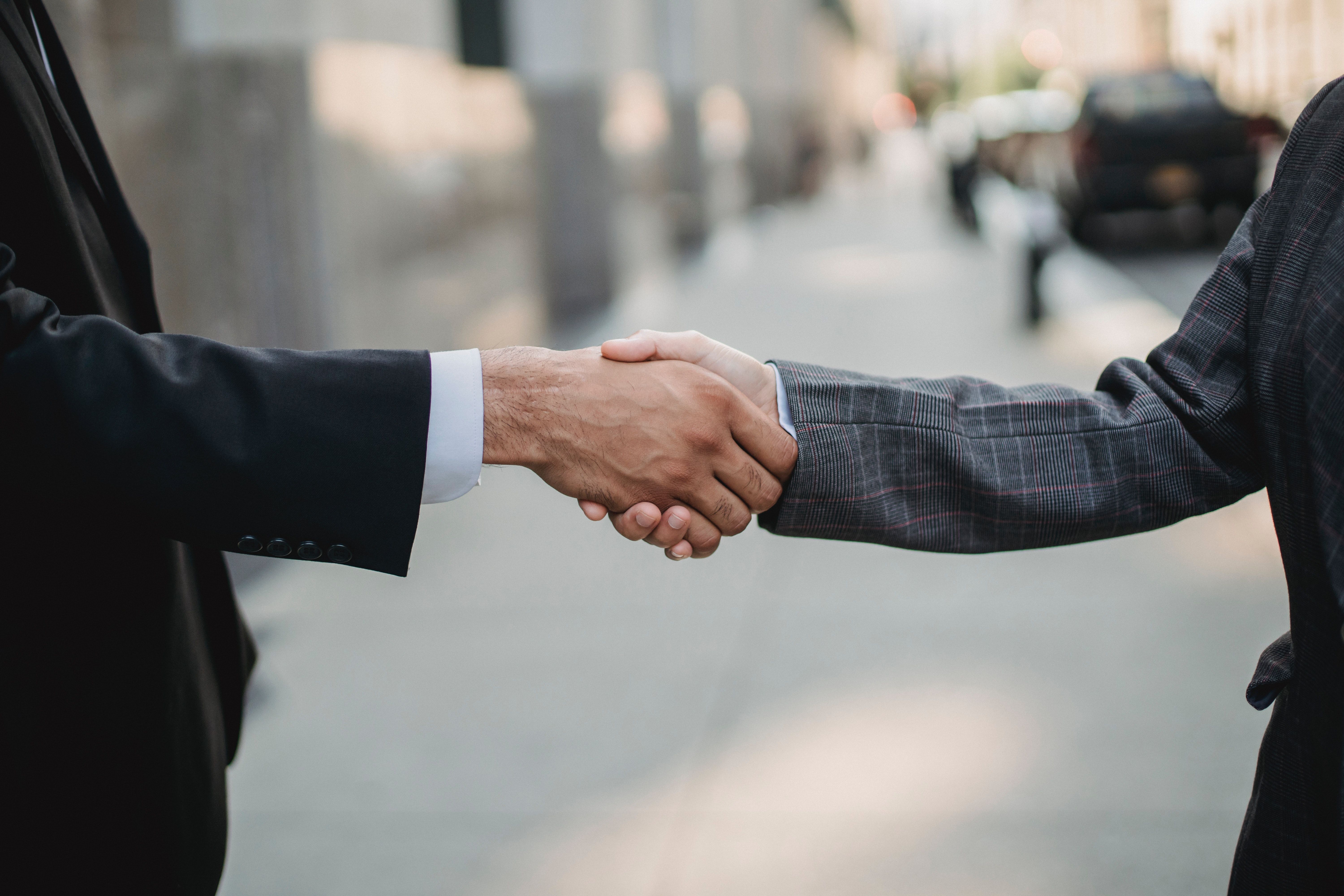 Two people shaking hands on a city sidewalk